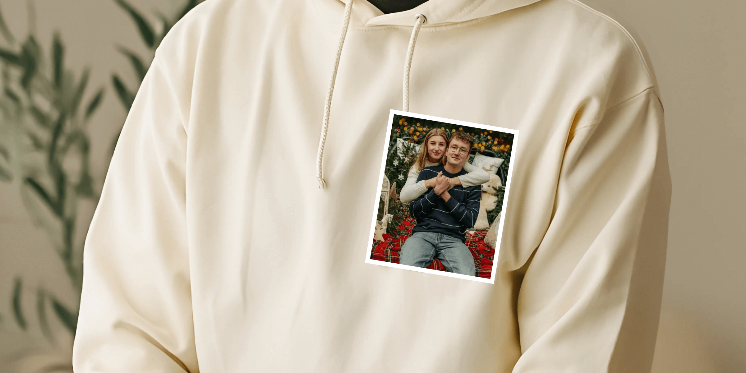 Detailní záběr na krémovou mikinu s fotografií objímajícího se páru na hrudi před vyšitím